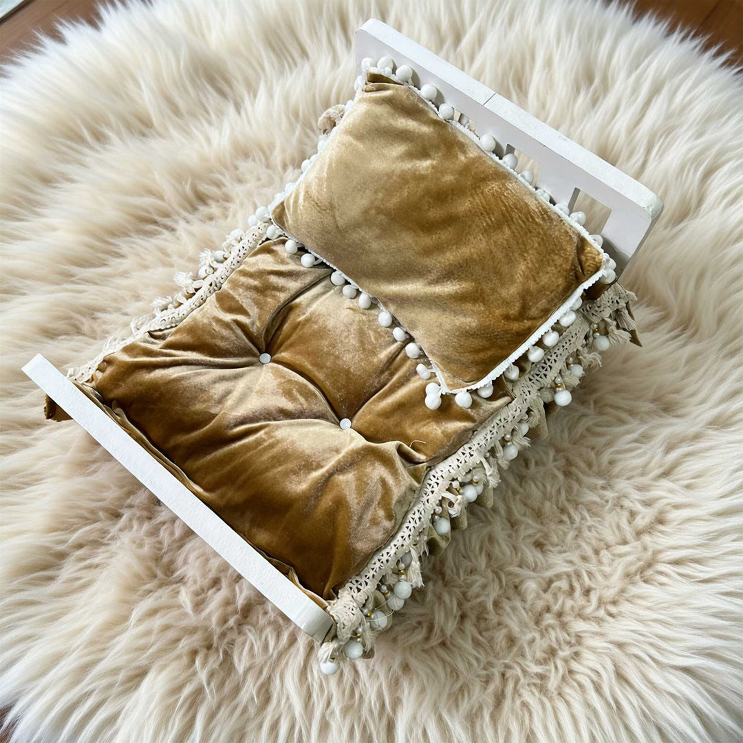 A 2-piece camel velvet tufted pom-pom trim posing cushion and pillow set for newborn photography.