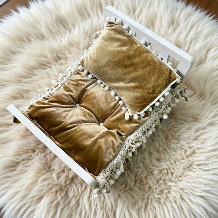 A 2-piece camel velvet tufted pom-pom trim posing cushion and pillow set for newborn photography.