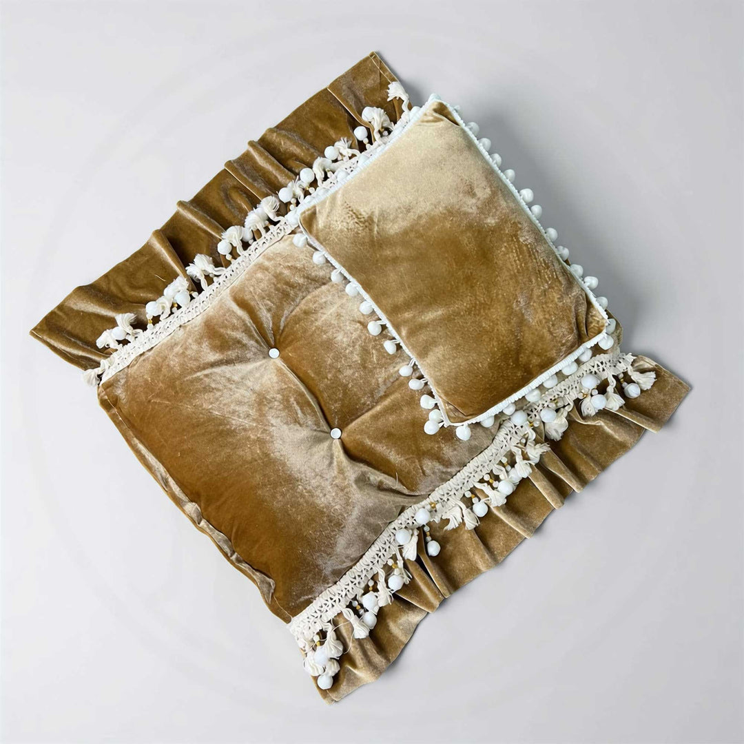 A 2-piece camel velvet tufted pom pom trim posing cushion and pillow set for newborn photography.