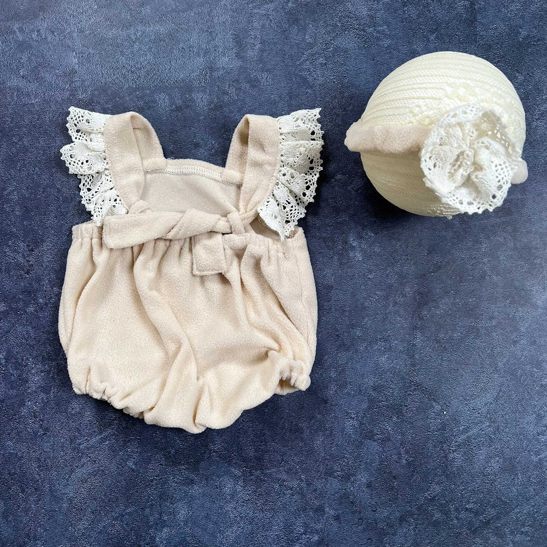 The back view of romper, flat lay shows a polar fleece romper with lace ruffle sleeves and headband with flower.