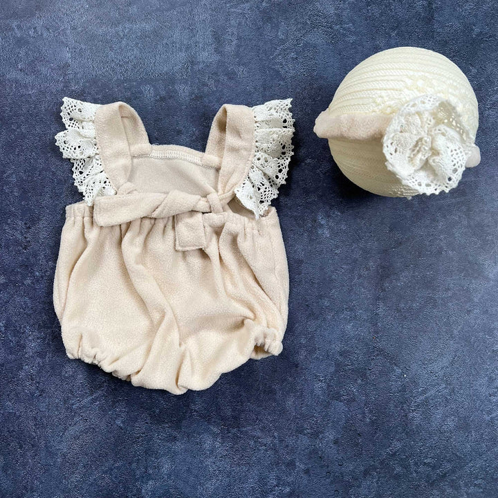 The back view of romper, flat lay shows a polar fleece romper with lace ruffle sleeves and headband with flower.
