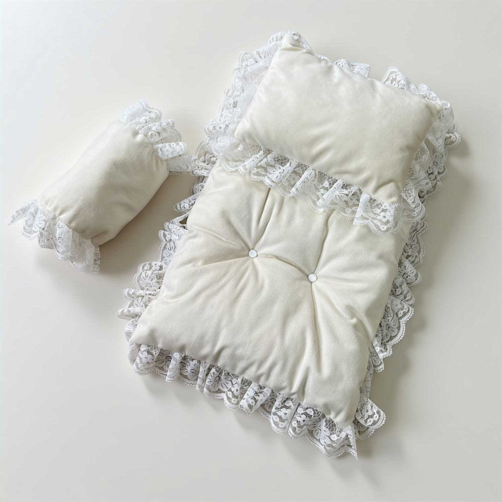 A 3-piece set featuring a tufted pearl white rug and pillows with lace trim for newborn photography.