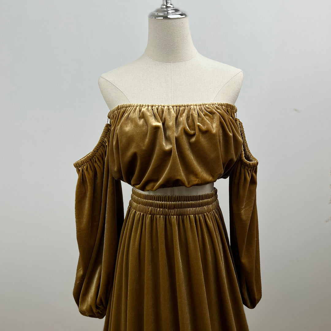 A mannequin displays a close-up of Belisama dress velvet off-shoulder top and floor-length skirt. The two-piece outfit has a ruffled skirt hem.