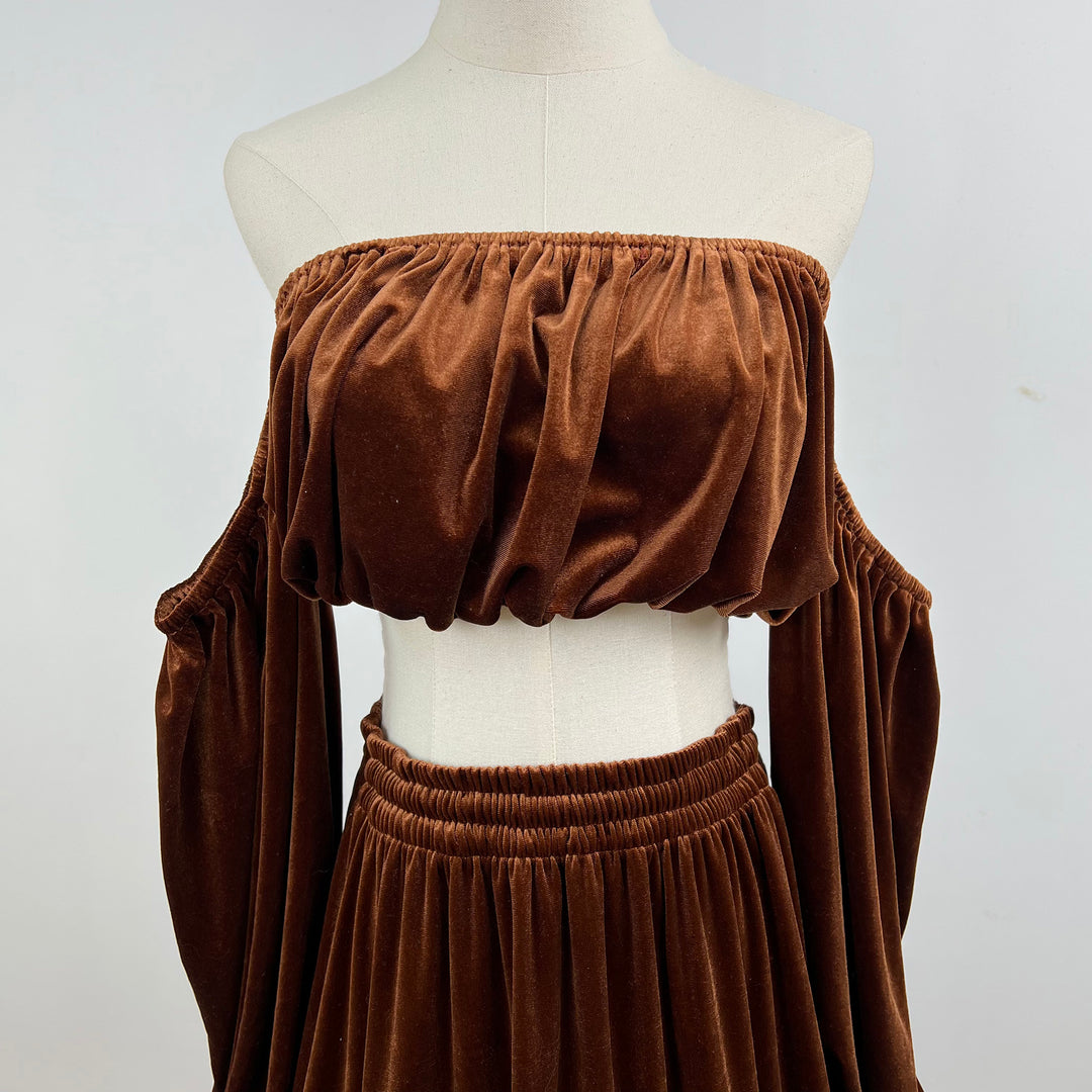 A brown velvet off-the-shoulder crop top and matching skirt set displayed on a cream mannequin torso against a light gray background.