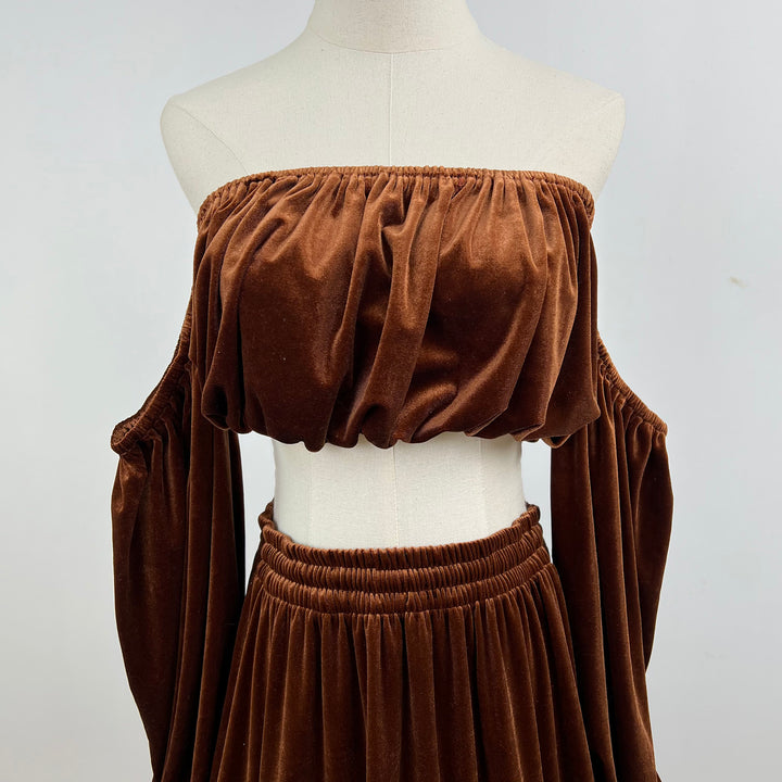 A brown velvet off-the-shoulder crop top and matching skirt set displayed on a cream mannequin torso against a light gray background.
