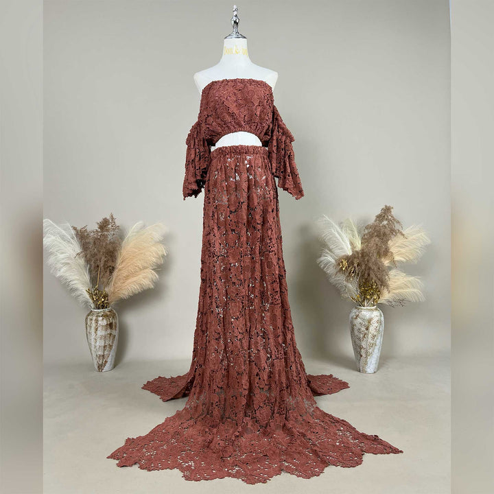 A terracotta two-piece lace maternity photography set displayed on a mannequin, featuring an off-the-shoulder ruffled crop top and a high-waisted floor-length skirt with a sweeping train