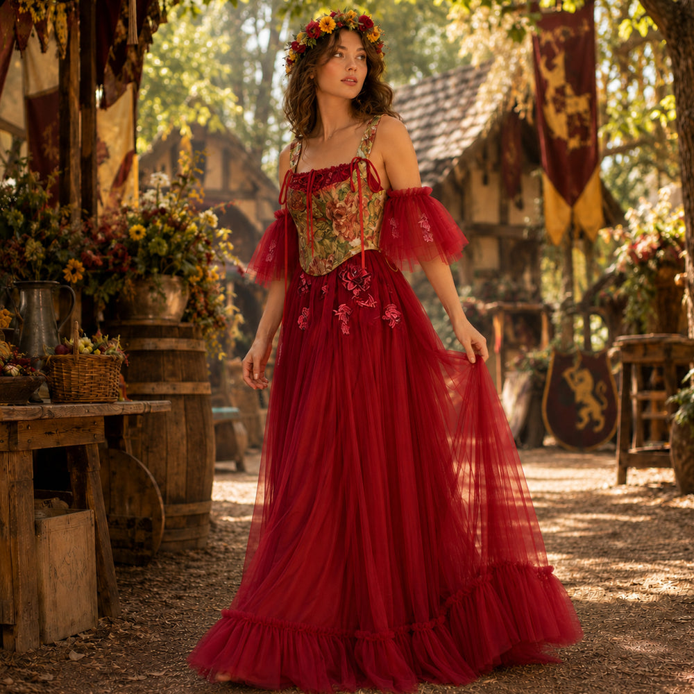 Full-length view of a woman wearing the Cailleach red tulle dress with a floral corset at a Renaissance festival.