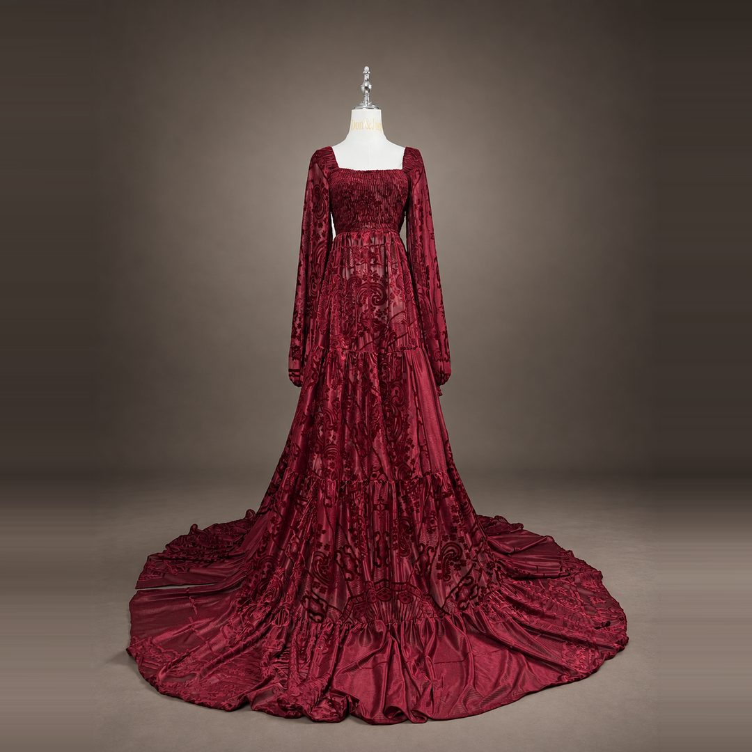A Calypso red wine long sleeve dress on a mannequin facing forward, train spread on the floor.