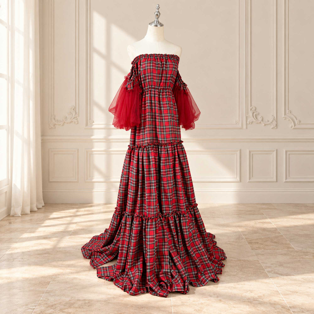A Celaeno plaid off-shoulder dress with red tulle sleeves on a mannequin, tiered skirt, train on the floor, indoors with a window and paneled wall.