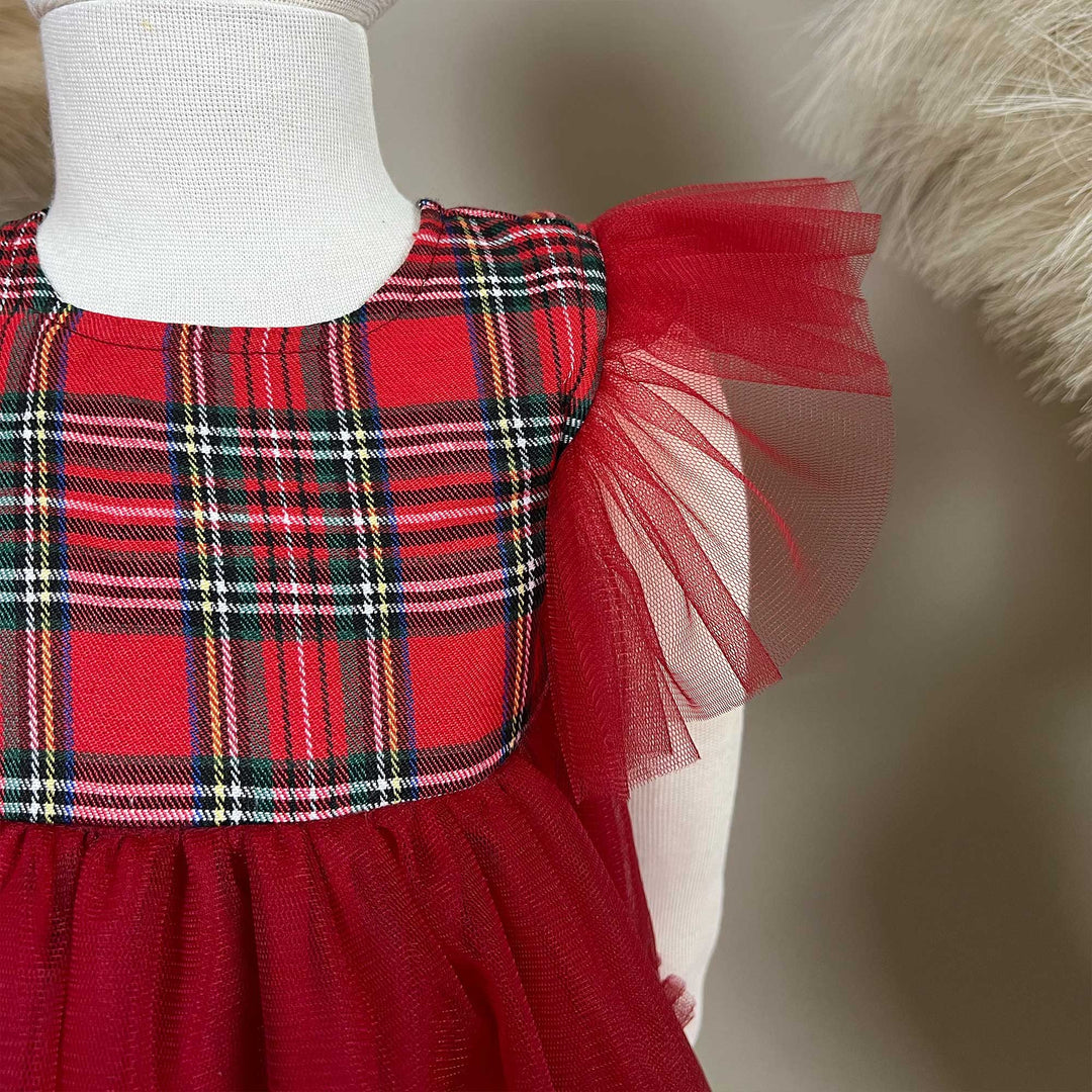 A close-up of the Cerridwen dress bodice, showing the plaid fabric, round neckline and one red tulle sleeve.