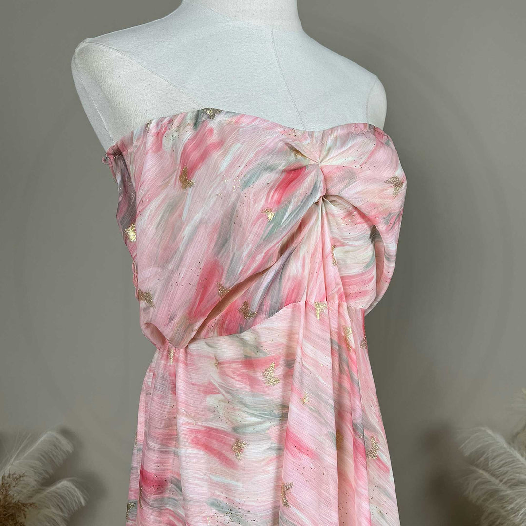 The upper body of a pink printed strapless gown with pleats.