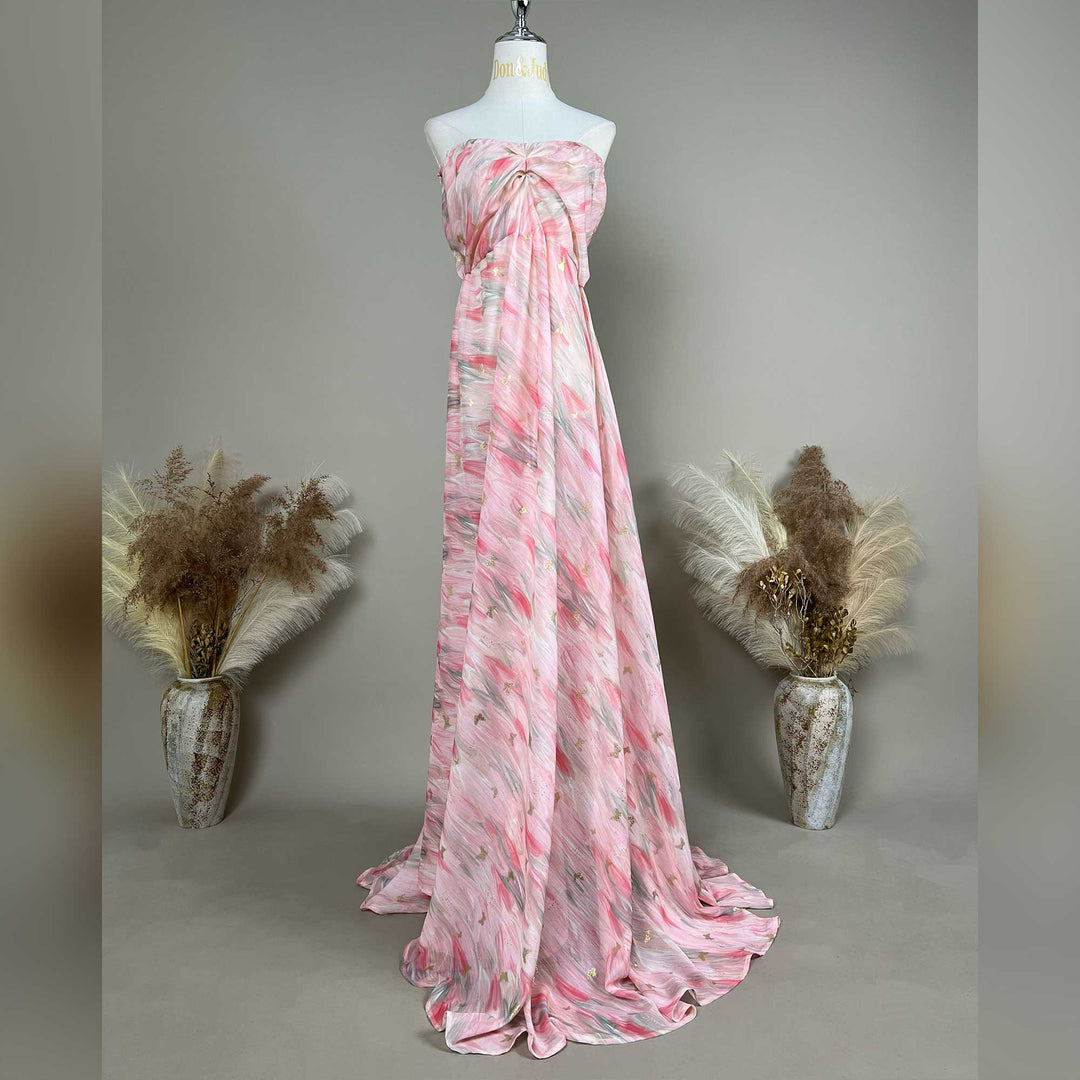 A mannequin displays a pink printed strapless gown with pleats and a train.