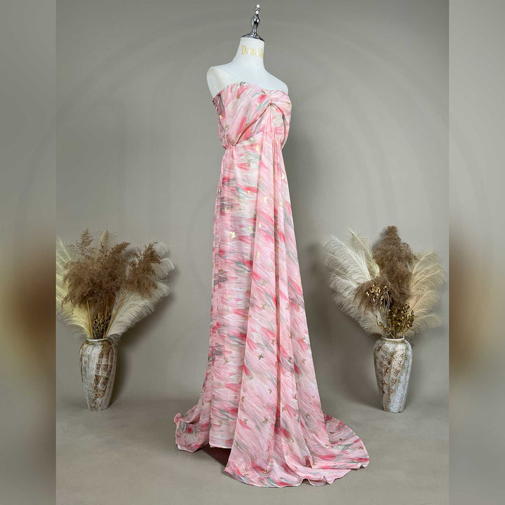 A mannequin displays a side view of a pink printed strapless gown with pleats and a train