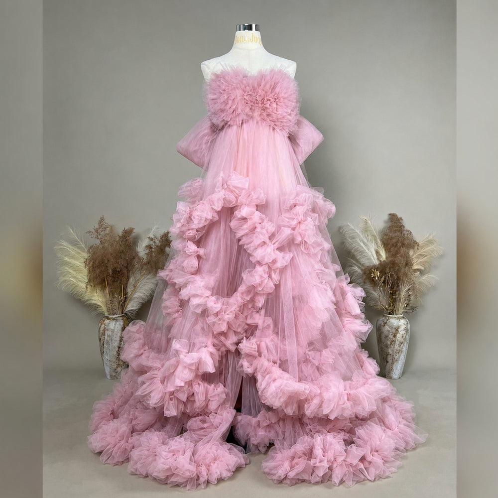A mannequin displays a pink strapless ruffled tulle gown; the dress features multi-layered ruffles and a train.