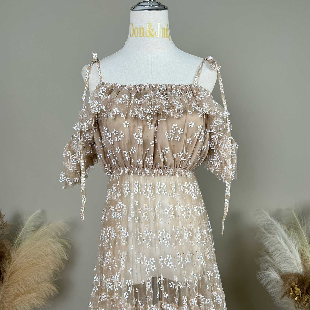 A khaki tulle dress with white floral embroidery and tie-shoulder straps, displayed on a mannequin.