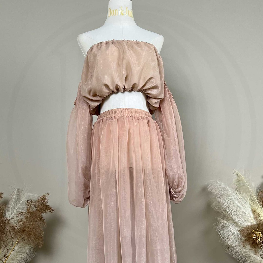 A mannequin displays a two-piece maternity set featuring an off-shoulder top and floor-length tulle skirt; the top has lantern sleeves.