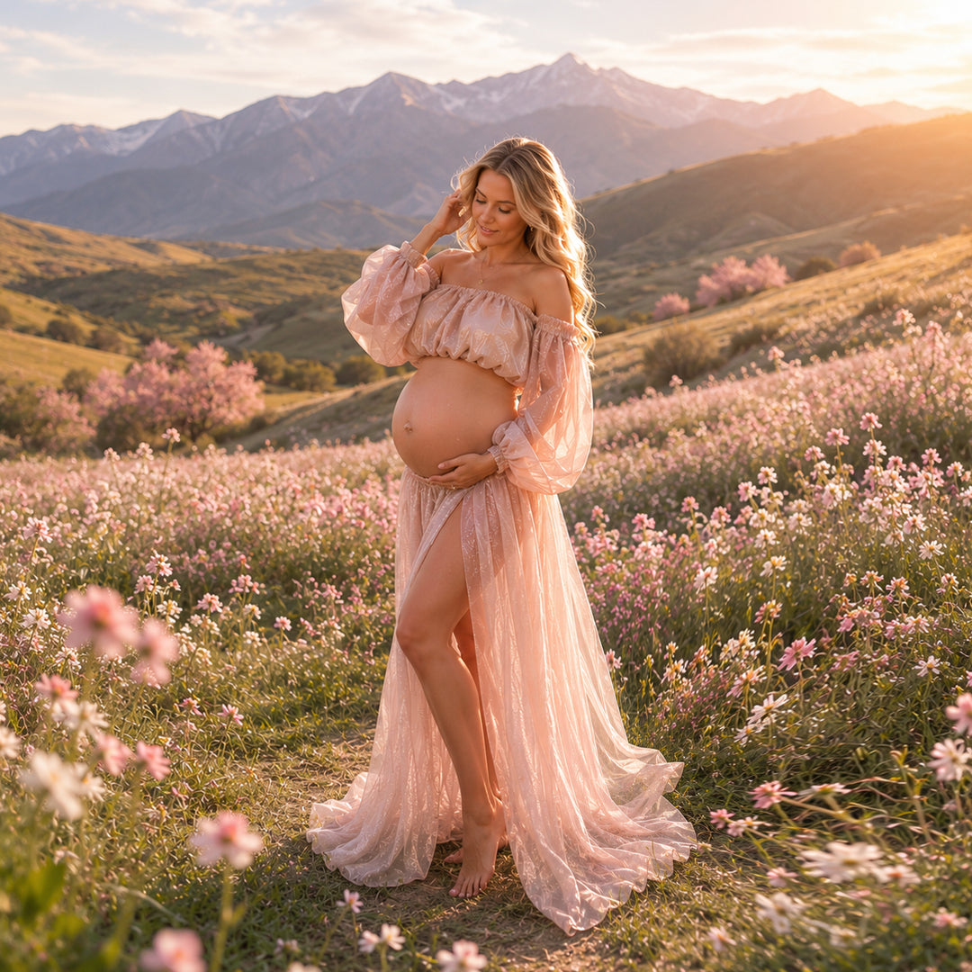 A pregnant woman stands in a flower field wearing a off-shoulder chiffon gown, holding her belly; the dress features puff sleeves and a high slit.