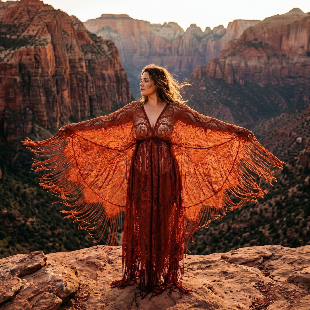 A woman stands on a rock wearing a rust lace fringe robe with arms spread; the robe features a deep V-neck and wide sleeves.