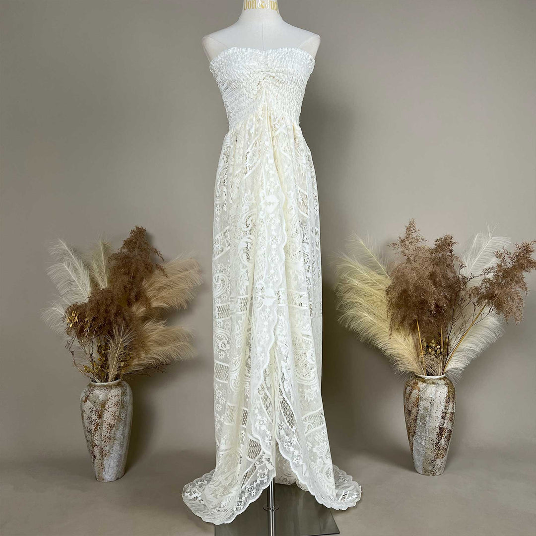 A mannequin displays a beige strapless lace gown with a ruched bodice and train; the dress features an openwork pattern.