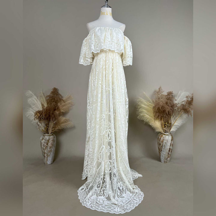 A mannequin displays a beige off-shoulder lace gown with ruffled sleeves and a train.