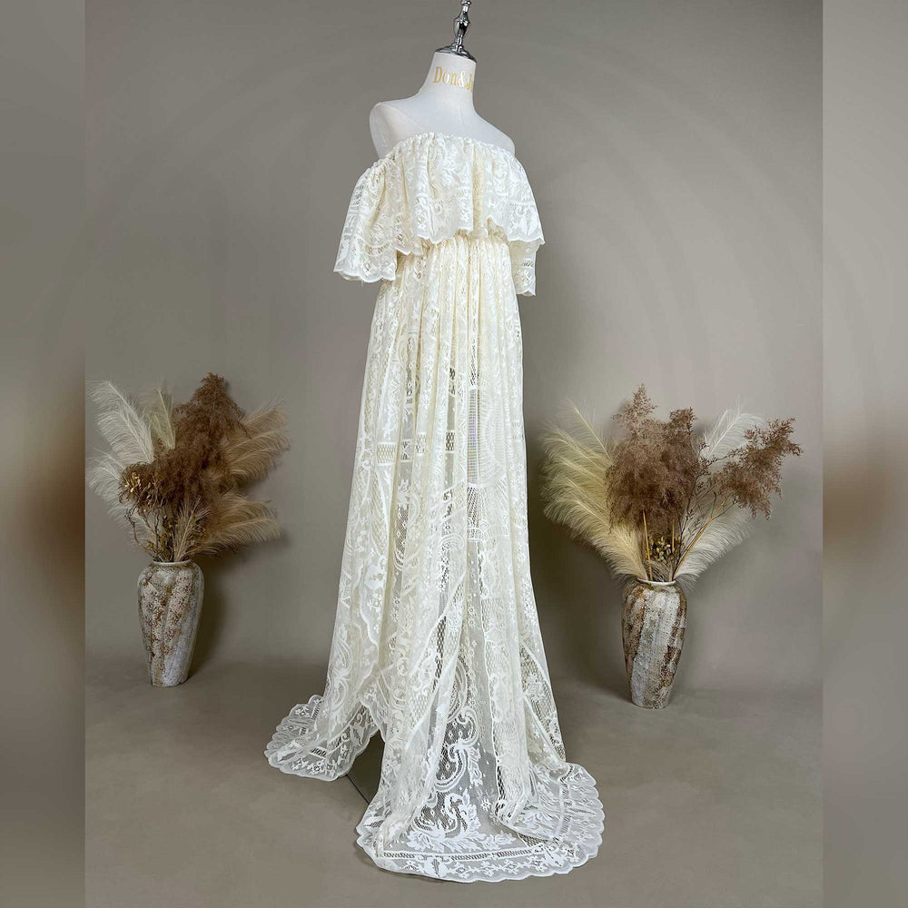 A mannequin shows a side view of beige off-shoulder lace gown with ruffled sleeves and a train; the dress features a sheer openwork structure