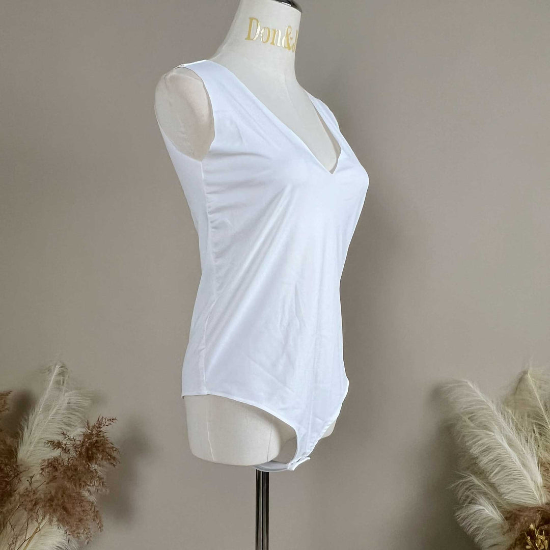 A mannequin shows a side view of a white sleeveless bodysuit, revealing the V-neck silhouette and fitted cut; the hem features a curved high-cut design.