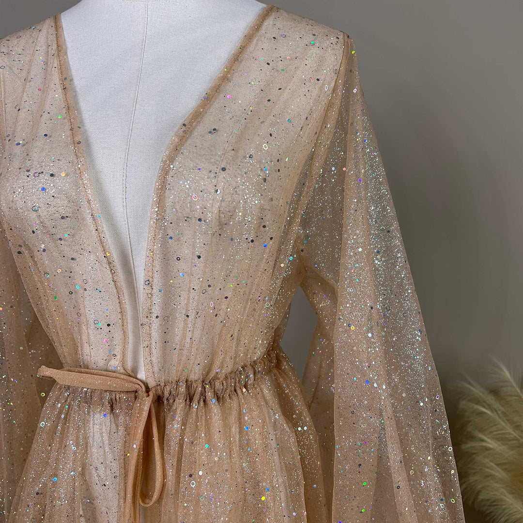 A mannequin displays the upper body of a champagne sequined V-neck robe with a tie waist and lantern sleeves; the fabric is transparent tulle.