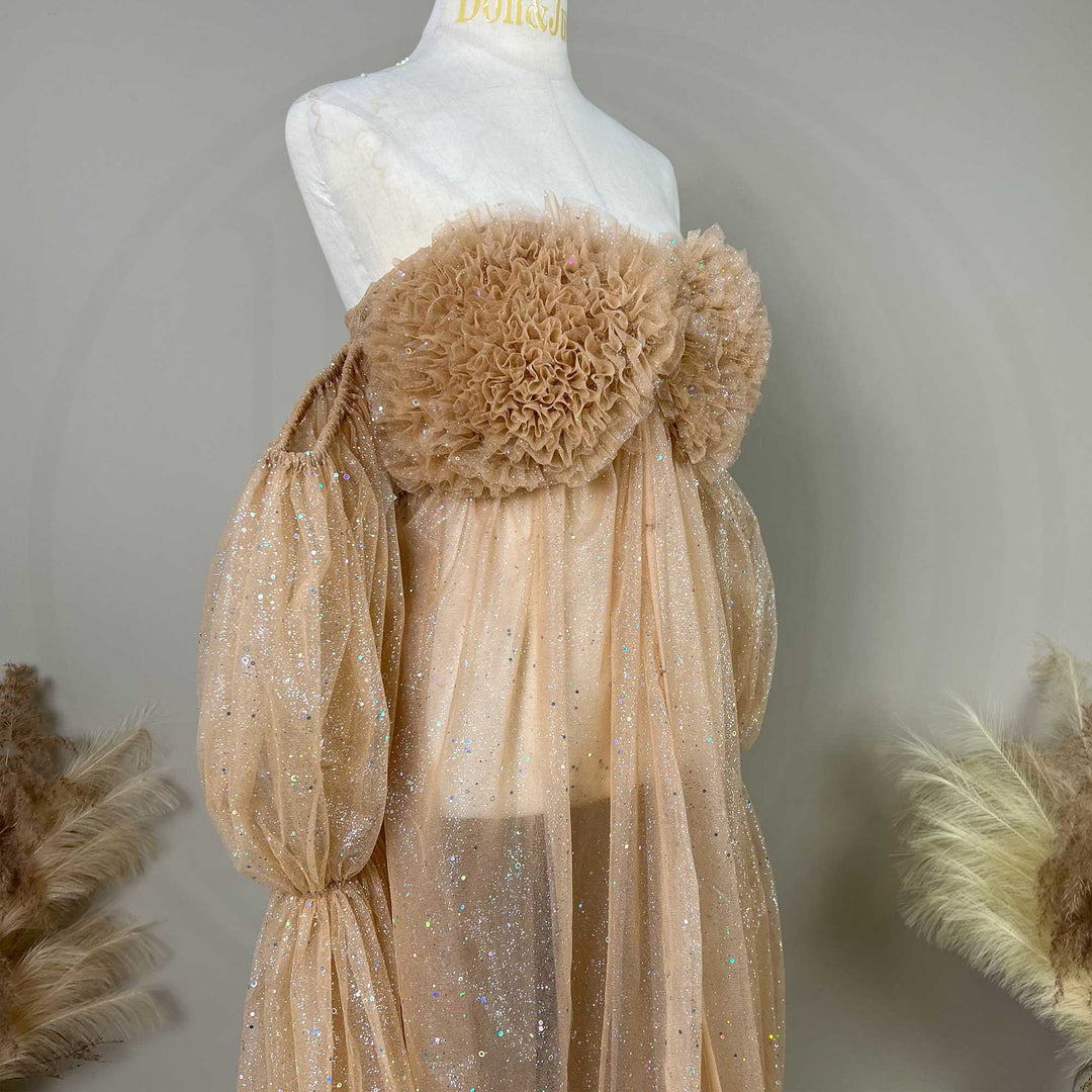 A mannequin displays the upper body of a khaki sequined off-shoulder gown with ruffled chest decor and puff sleeves.