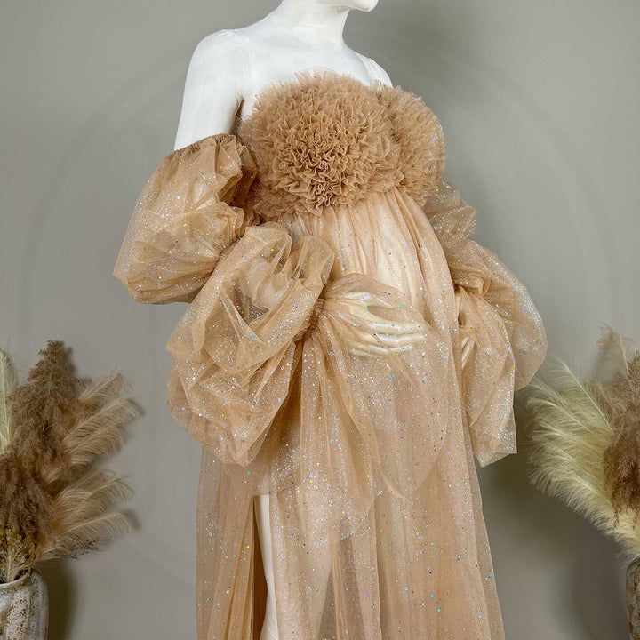 Close up of mannequin displays a khaki sequined off-shoulder maternity gown with feather chest decor and a split train.