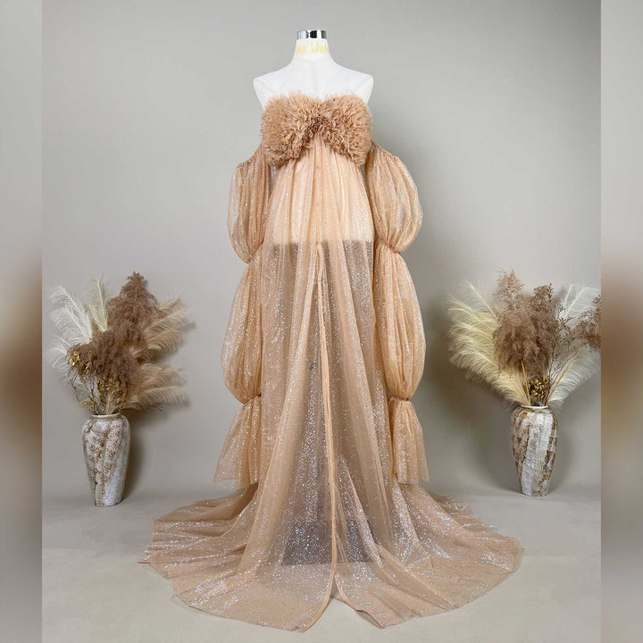 A mannequin displays a khaki sequined off-shoulder gown with feather chest decor and segmented puff sleeves.