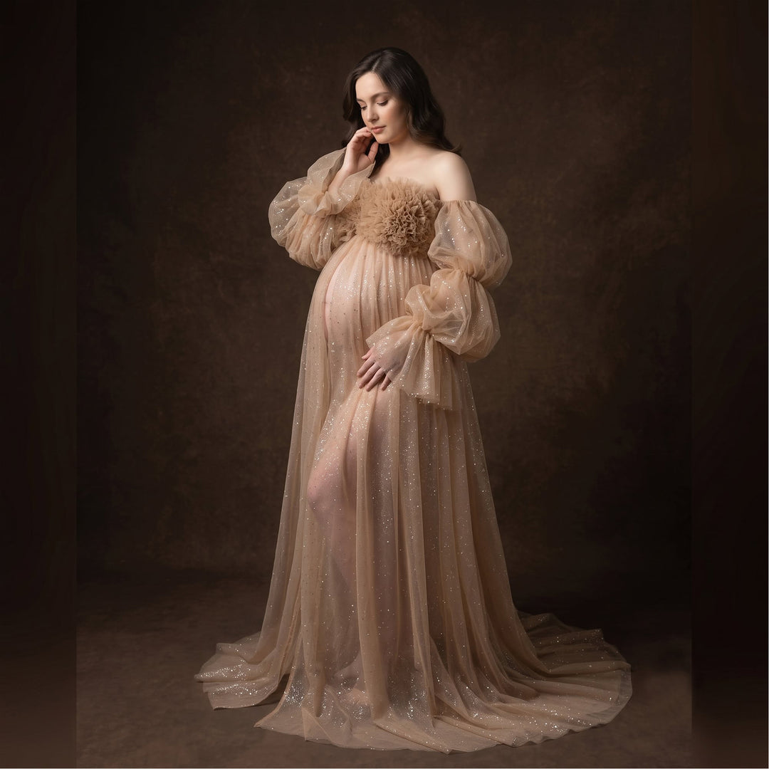 A pregnant model in a khaki sequined off-shoulder gown stands against a dark background, one hand on belly.