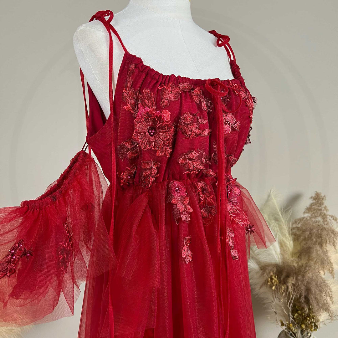 Close-up detail of the red floral embroidered off-shoulder tiered ruffle maternity photography dress, highlighting the front neckline and gathered waist design details.