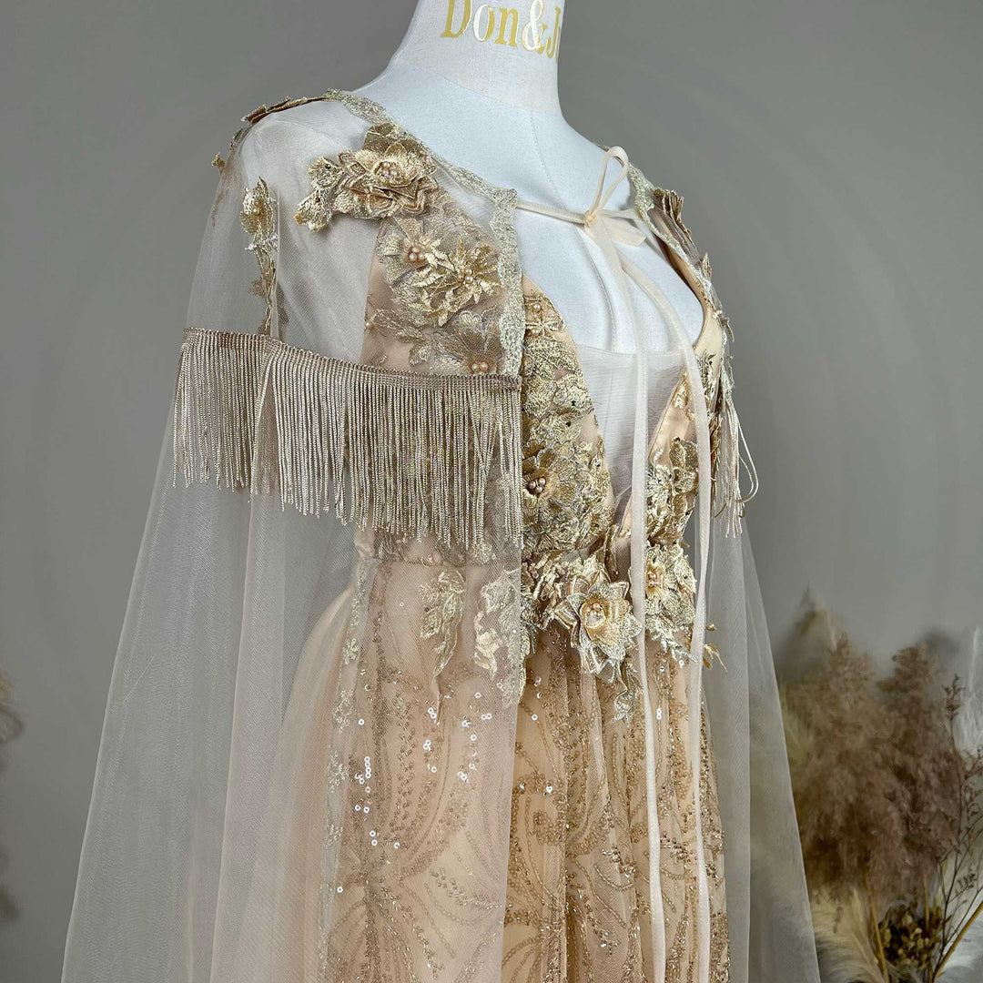 A mannequin displays the gown's shoulder details, including 3D flowers, fringe cuffs, and a tulle cape.