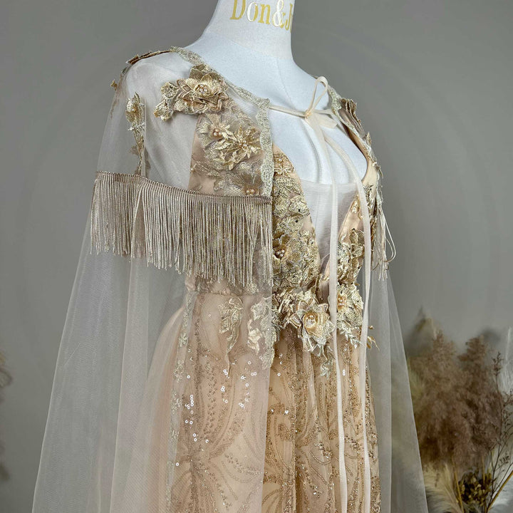 A mannequin displays the gown's shoulder details, including 3D flowers, fringe cuffs, and a tulle cape.