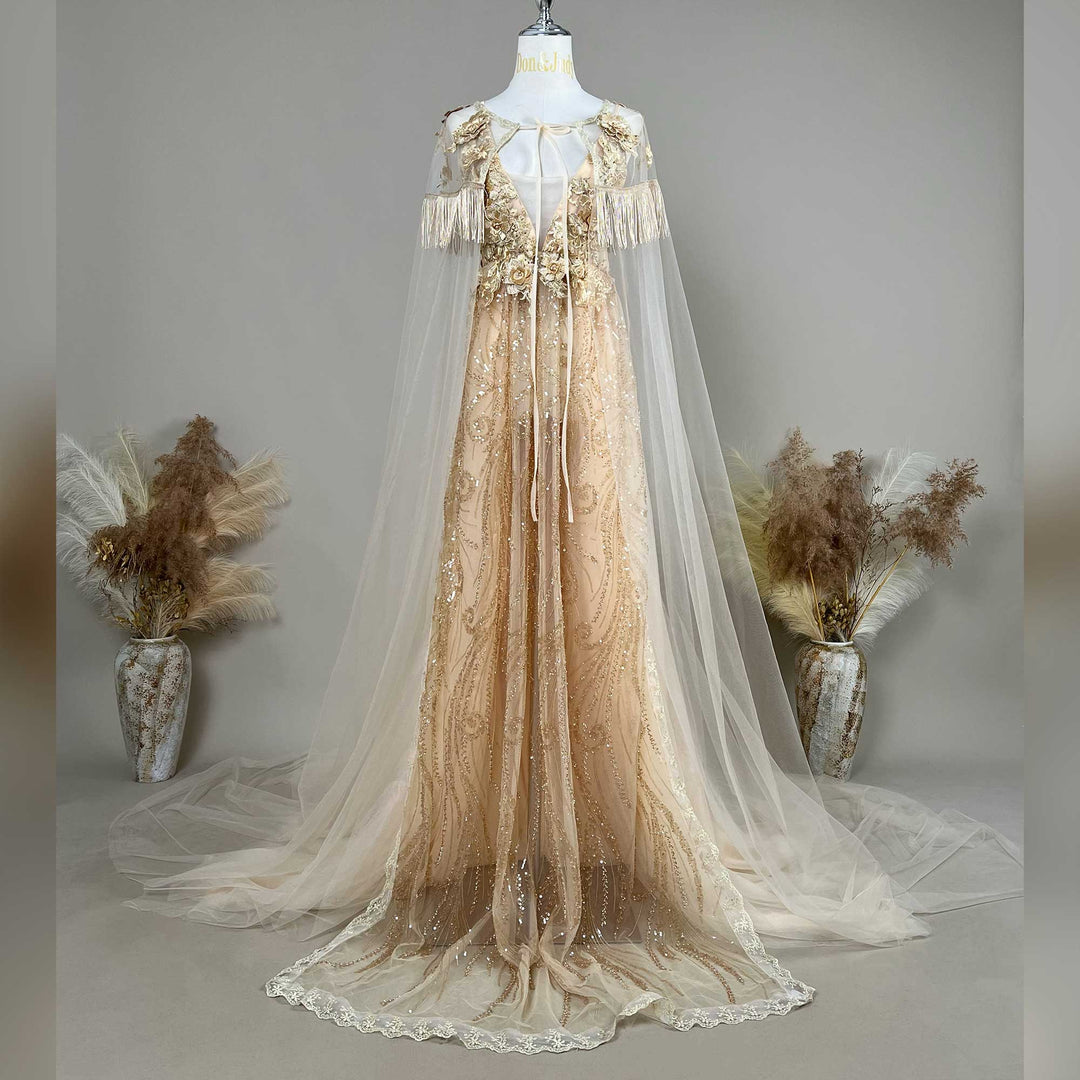 A gold sequined gown with a tulle cape is displayed on a mannequin, featuring fringe cuffs and a train skirt.
