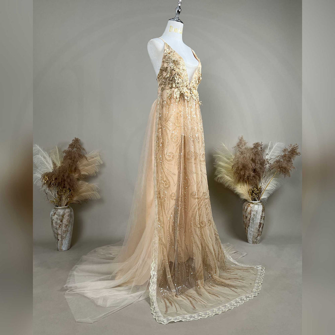 A mannequin displays a gold sequined spaghetti strap gown with a deep V-neck, 3D floral decorations, and a train skirt.