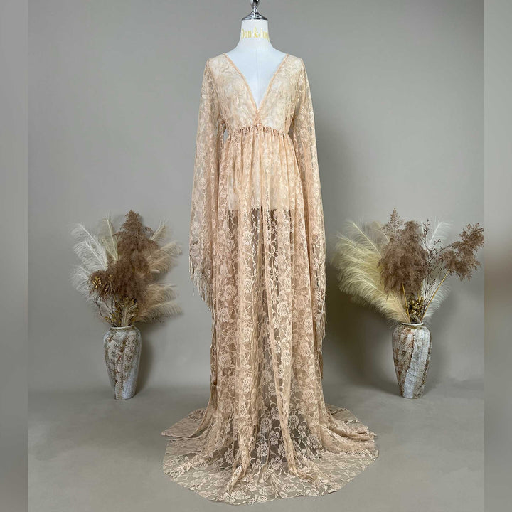 A khaki lace V-neck gown is displayed on a mannequin, featuring a ruched high waistline, fringe cuffs, and a floor-sweeping skirt.