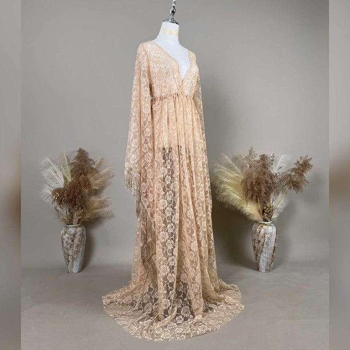 A khaki lace V-neck gown is displayed on a mannequin, featuring a ruched high waistline, fringe cuffs, and a floor-sweeping skirt.