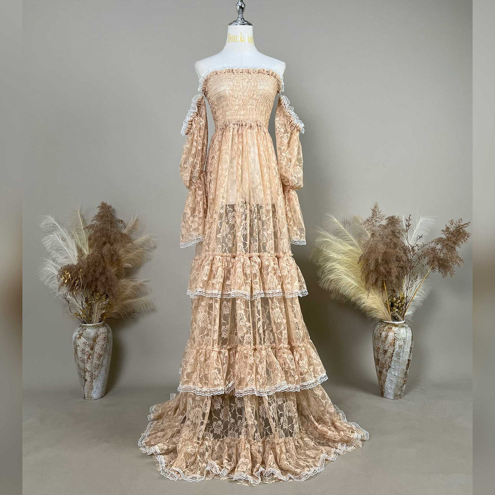 A khaki lace off-shoulder gown is displayed on a mannequin, featuring a shirred bodice, tiered ruffled sleeves, and a multi-layered cake skirt.
