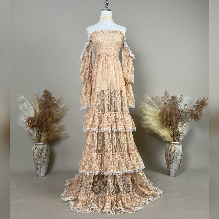 A khaki lace off-shoulder gown is displayed on a mannequin, featuring a shirred bodice, tiered ruffled sleeves, and a multi-layered cake skirt.