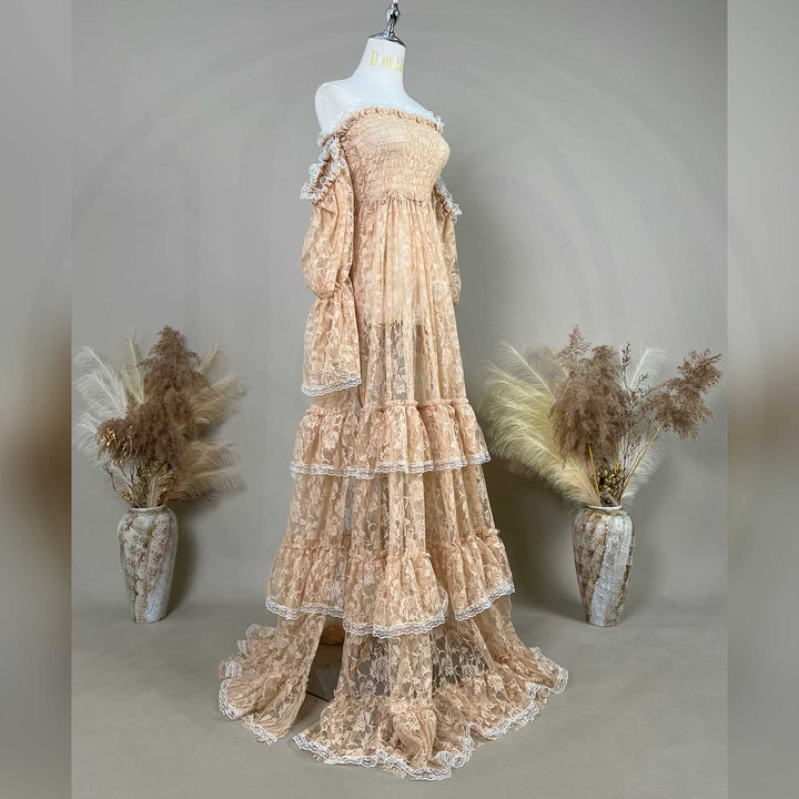 A khaki lace off-shoulder gown is displayed on a mannequin, featuring a shirred bodice, tiered ruffled sleeves, and a multi-layered cake skirt.
