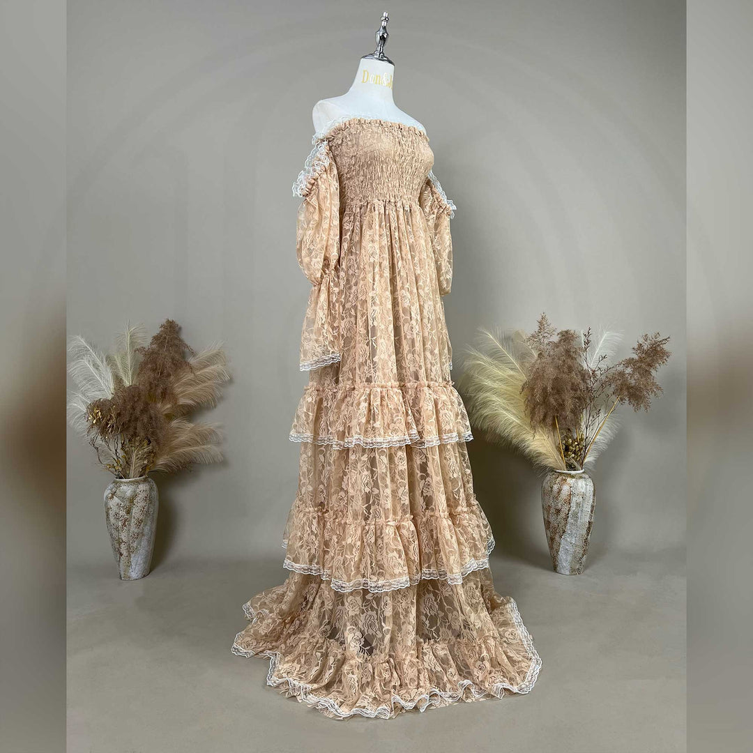 A khaki lace off-shoulder gown is displayed on a mannequin, featuring a shirred bodice, tiered ruffled sleeves, and a multi-layered cake skirt.