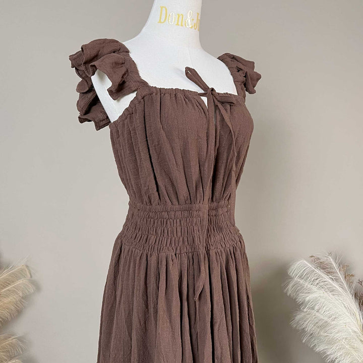 A coffee Tethys gown is displayed on a mannequin, featuring ruffled short sleeves, a front tie, and an elasticated waist