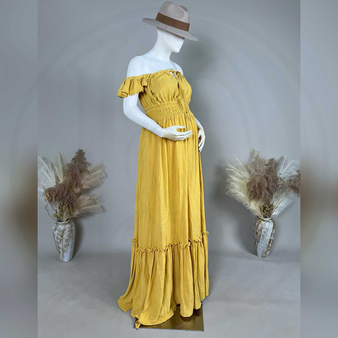 A Tethys gown is displayed on a mannequin, featuring ruffled short sleeves, a front tie, elasticated waist, tiered ruffled hem, and train.
