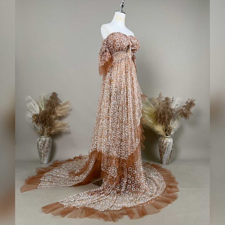 A Khaki Tyche is displayed on a mannequin with dried flowers on both sides; the dress features a train and a ruffled hem structure.