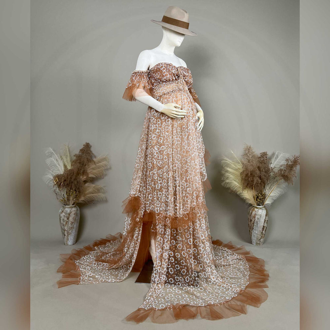 A Khaki Tyche is displayed on a mannequin with dried flowers on both sides; the dress features a train and a ruffled hem structure.