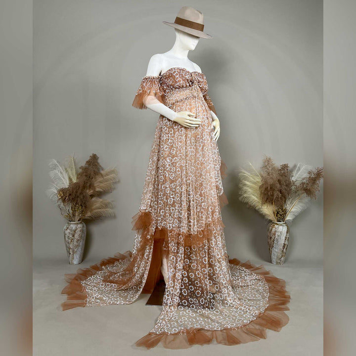 A Khaki Tyche is displayed on a mannequin with dried flowers on both sides; the dress features a train and a ruffled hem structure.