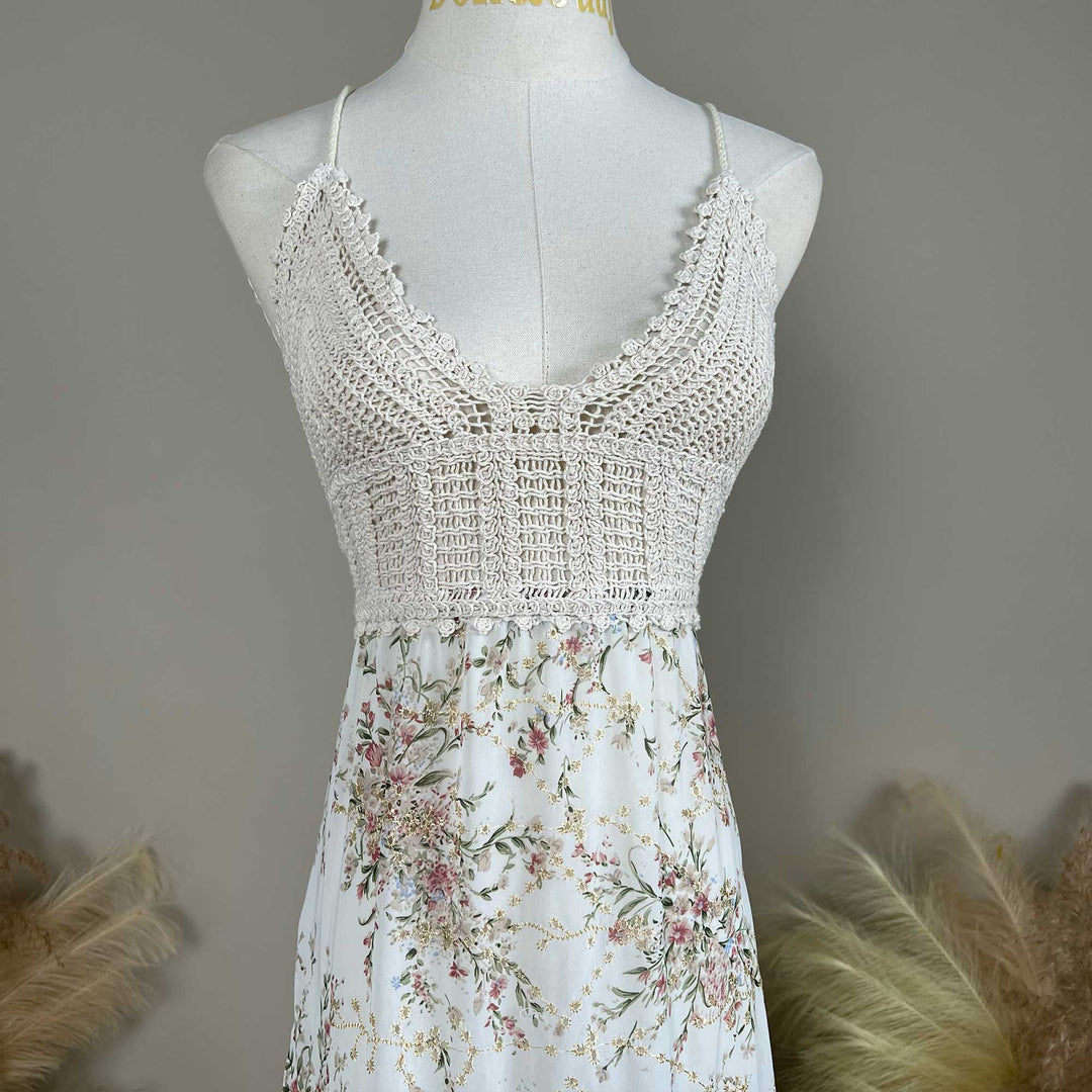The Urania,an apricot bottom floral maternity maxi dress with spaghetti straps, a crochet bodice details, displayed on a mannequin.
